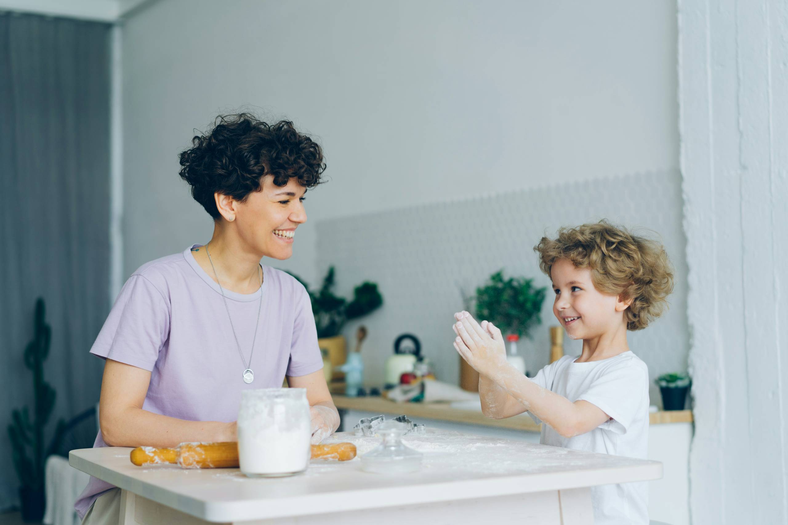A parent and child clapping together in the kitchen