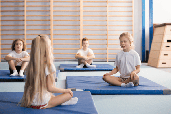 A group of children sitting on gymnastics mats