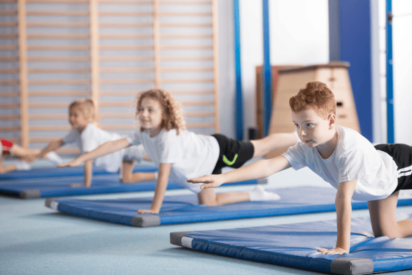 A group of children practising gymnastics exercises on mats
