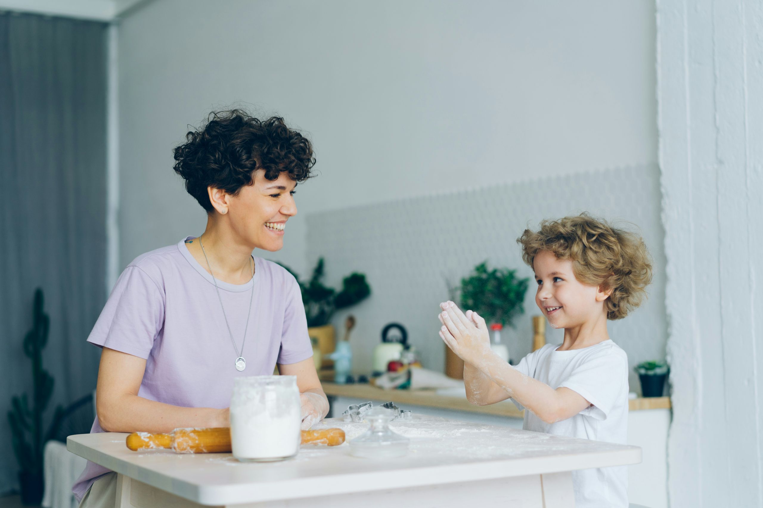 A parent and child clapping together in the kitchen